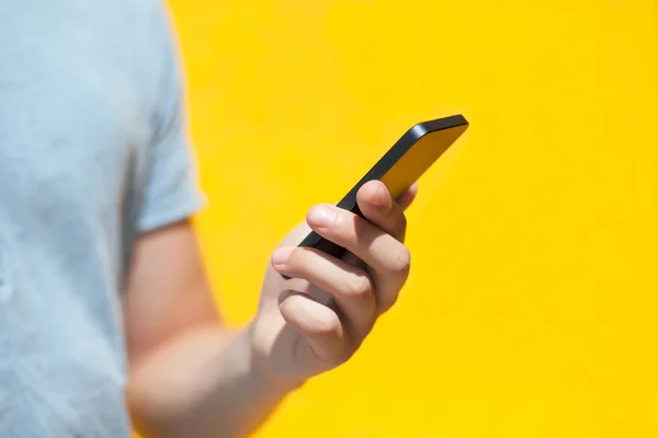Хлопчик тримає дотичний телефон на жовтій стіні — стокове фото