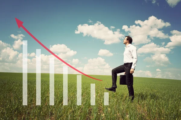 Businessman in the field rises on the chart with red arrow up — Stock Photo, Image