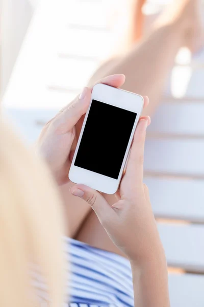 Flicka i en baddräkt liggande på en schäslong med touch telefon — Stockfoto