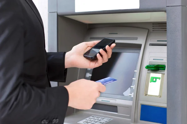 atm duran ve bir kredi kartı tutan işadamı ve