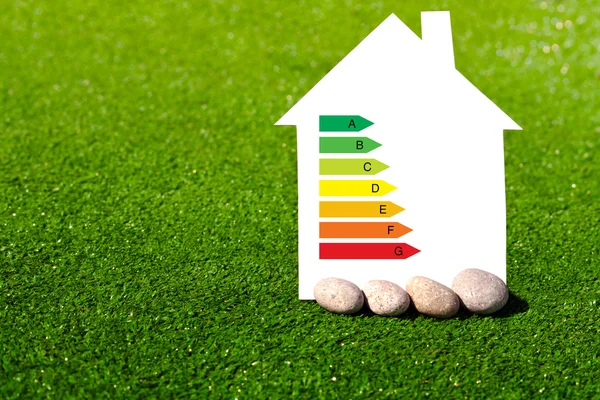 Дом со знаком энергосбережения на фоне травы — стоковое фото