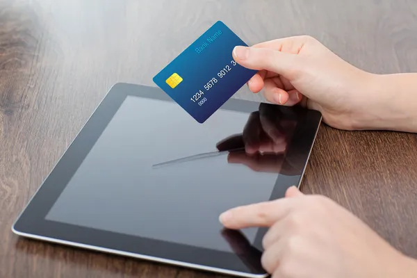 female hands holding credit card and a computer on the table in