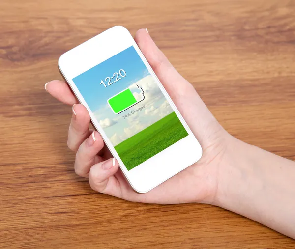 Woman hand holding a touch white phone with charged battery on a — Stock Photo, Image