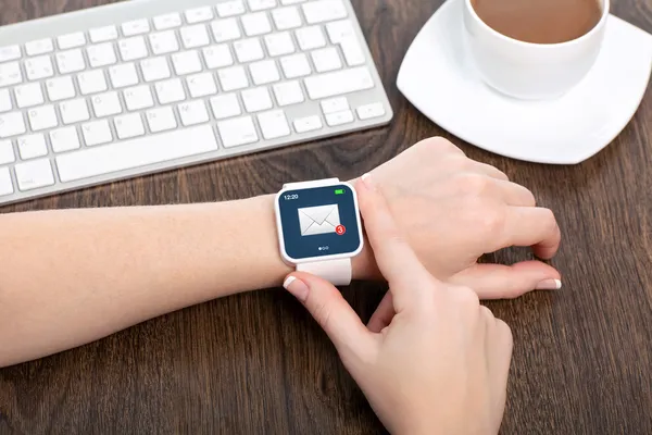 Weibliche Hand mit Smartwatch mit E-Mail auf dem Bildschirm in einem Offic — Stockfoto