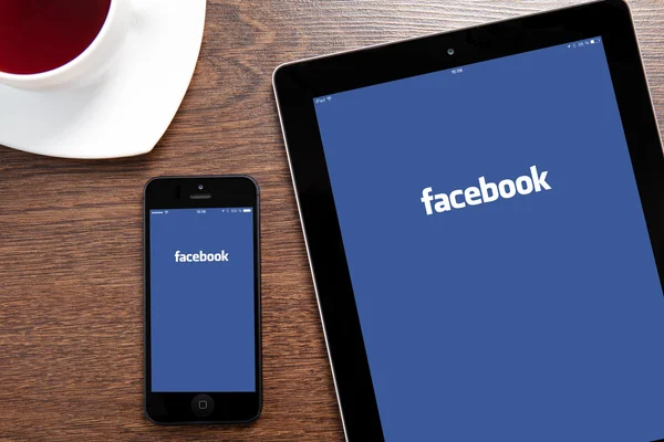 IPad e IPhone con Facebook su uno schermo — Foto Stock