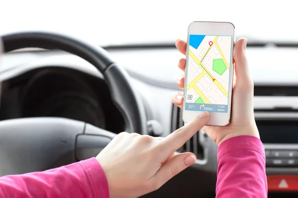 Vrouwelijke bestuurder hand met een telefoon met interface navigator op een — Stockfoto