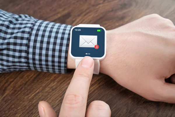 Manos masculinas con smartwatch blanco con el email en la pantalla sobre un — Foto de Stock