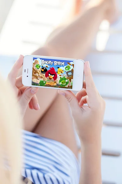 Girl lying on a chaise lounge holding iPhone with Angry Birds on — Stock Photo, Image