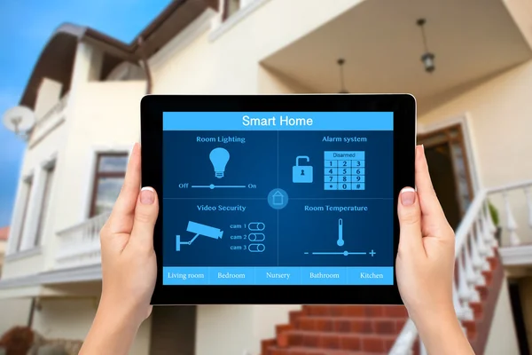 Le mani femminili tengono un tablet con sistema smart house sul dorso — Foto Stock