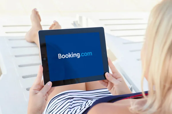 Girl lying by the pool and holding ipad with app Booking on the — Stock Photo, Image