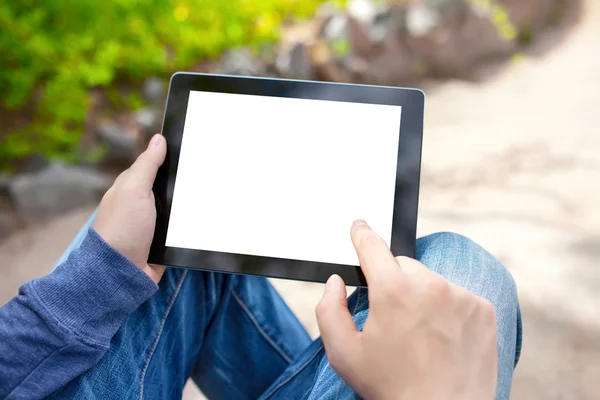 Człowiek siedzi w parku i trzymając tablet z ekranem na białym tle — Zdjęcie stockowe