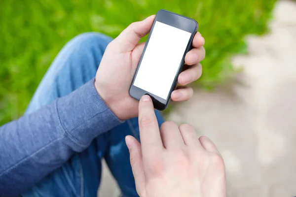 Man sitting in the park and holding phone with isolated screen — Stock Photo, Image