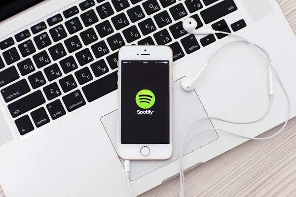 White iPhone 5s with site Spotify on the screen and headphones l — Stock Photo, Image
