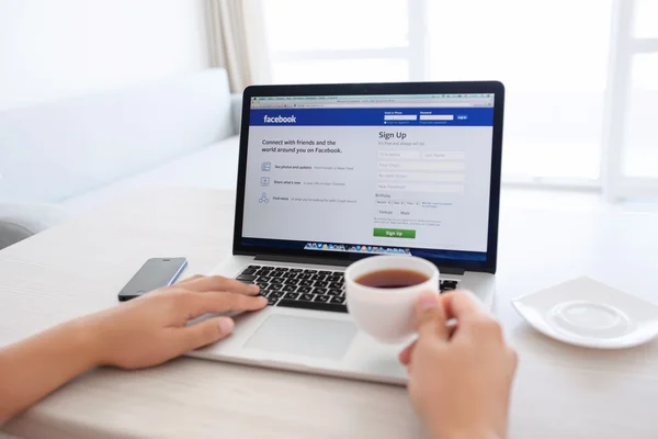 Man sitting at the MacBook retina with site Facebook on the scre — Stock Photo, Image