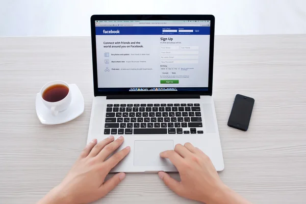Man sitter på näthinnan macbook med webbplatsen facebook på skä — Stockfoto