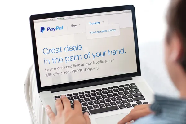 Homem sentado na retina MacBook com o site PayPal na tela — Fotografia de Stock