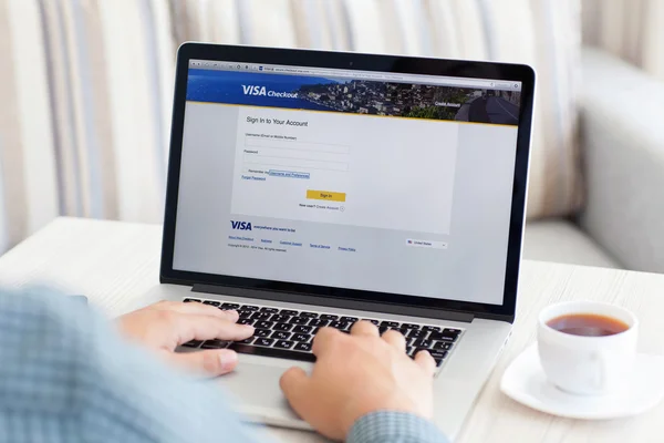 Homme assis à la rétine MacBook avec le site Visa à l'écran — Photo