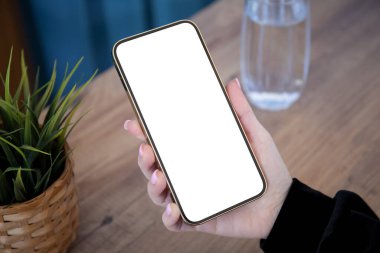 Kadın elleri, kafeteryadaki tek bir ekranla telefonu tutuyor.