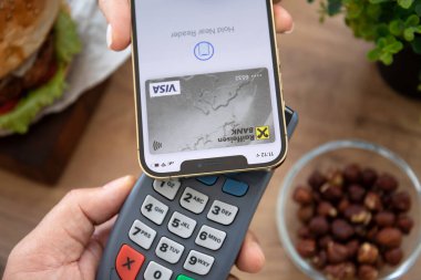Alanya, Türkiye - 23 Ekim 2021: Elde iPhone 12 Pro Max ve Apple Pay ekranda ve çevrimiçi geçiş terminali hamburger.