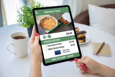 Kadın elleri kafeteryada yemek dağıtım uygulamalı bilgisayar tabletini ekranda tutuyor. 