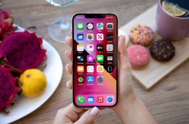 Alanya, Türkiye - 11 Ekim 2021: iPhone 12 Pro Max Gold 'un ev ekranı IOS 15 ile el ele tutuşması.