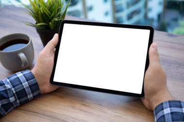 Ofisteki masadaki izole ekranlı bilgisayar tabletini tutan erkek elleri 