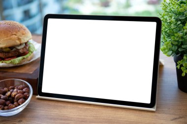Kafedeki masa arkası hamburgerinde izole ekran içeren bilgisayar tableti 