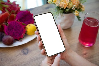 Kadın eli telefonu tutuyor. Kafede meyvelerle dolu bir ekranın üzerinde. 