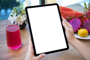 Kafedeki meyvelerin arka planında izole ekranlı bilgisayar tableti tutan kadın elleri 