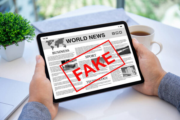 мужчины держат в руках планшет с мировыми новостями и слово подделка на экране в офисе