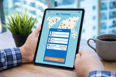 Havalimanında hava biletlerini arayan uygulamalı erkek eller bilgisayar tableti tutuyor.