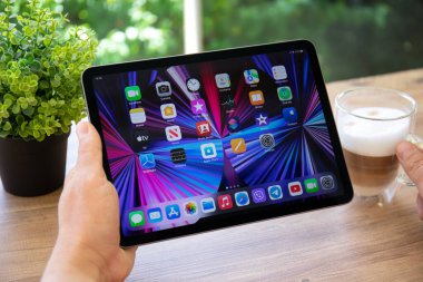 Alanya, Turkey - April 25, 2022: Man hand holding iPad Air IOS 15 with widget on the home screen. iPad was created and developed by the Apple inc