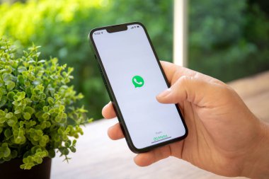Alanya, Turkey - April 25, 2022: Man hand holding iPhone 13 Pro Graphite with social networking service messenger WhatsApp on the screen.