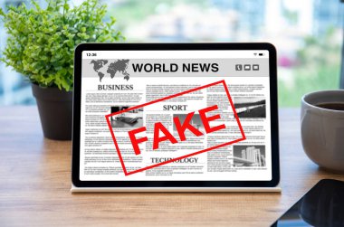 Ofisteki masadaki ekranda sahte haber ve kelime içeren bilgisayar tableti