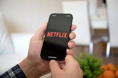 Alanya, Türkiye - 16 Şubat 2022: iPhone 13 Pro Graphite 'ı elinde tutan adam çok uluslu eğlence şirketi Netflix ekranda yayın yapan medya ve video sunuyor