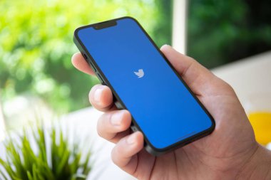 Alanya, Turkey - April 26, 2022: Man hand holding iPhone 13 with social networking service Twitter on the screen