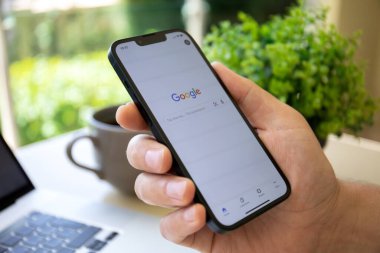 Alanya, Turkey - April 28, 2022: Man hand with holding Apple iPhone 13 with social networking service Google on the screen