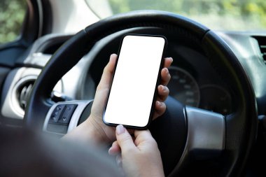female hands hold phone with isolated screen background of steering wheel in car