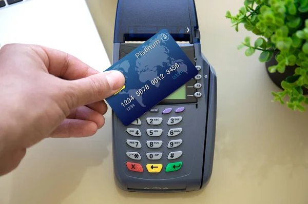 man hand holding plastic card and pay pass online terminal in the store