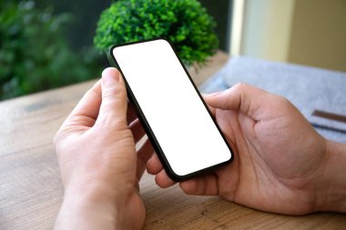 Ofisteki masanın izole ekran arka planına sahip erkek eller telefonu tutuyor.