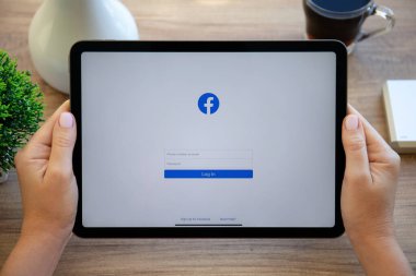 Alanya, Türkiye - 11 Ekim 2022: Kadın el ele tutuşması iPad Air Space Gray ve sosyal ağ hizmetleri kuryesi Facebook ekranda.