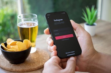 Alanya, Türkiye - 4 Ekim 2022: Kafedeki ekranda sosyal ağ servisi Instagram ile iPhone 14 'ü tutan adam