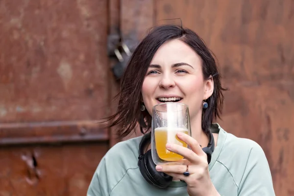 Śmiejąca Się Dziewczyna Słuchawkami Szklanką Piwa Ręku — Zdjęcie stockowe