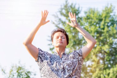 Yetişkin bir kadın Qigong nefes egzersizi yapıyor.