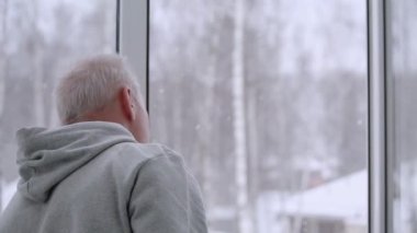 Adam açık pencereden dışarı bakar ve kapıyı kapatır.
