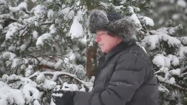 Un hombre juega bolas de nieve en una nevada — Vídeos de Stock