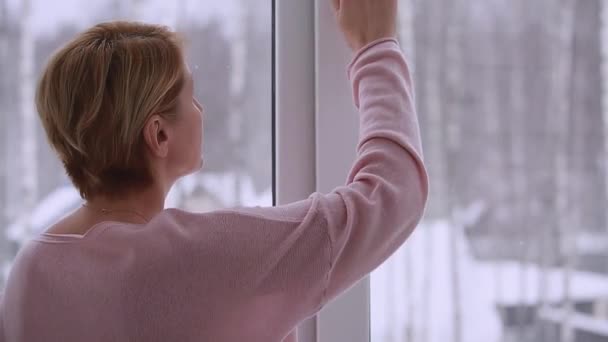 A woman looking out the window in winter — Vídeos de Stock