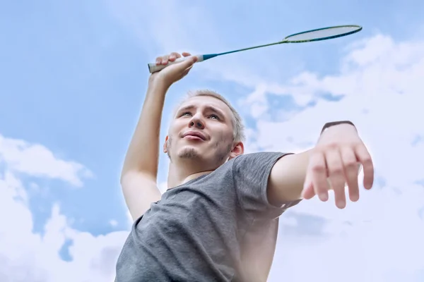 Портрет блондина с бадминтонной ракеткой в руке на фоне облачного неба — стоковое фото