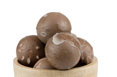 Beyaz arka planda izole edilmiş ahşap bardaktaki çikolata topları.