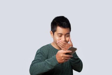 Portrait of Asian man using smartphone surprised news isolated on gray background.